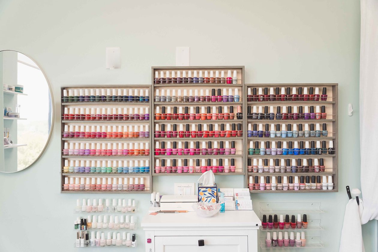 Nail technician suite at WanderLux with a full wall of OPI polish displayed on wooden racks