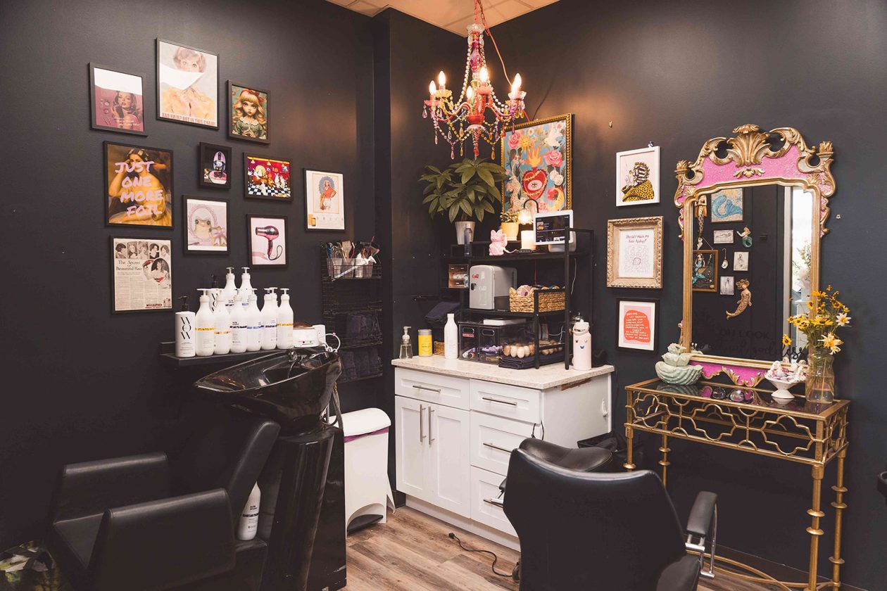 Dramatic black salon suite at WanderLux with gallery wall, gold mirror and pink chandelier