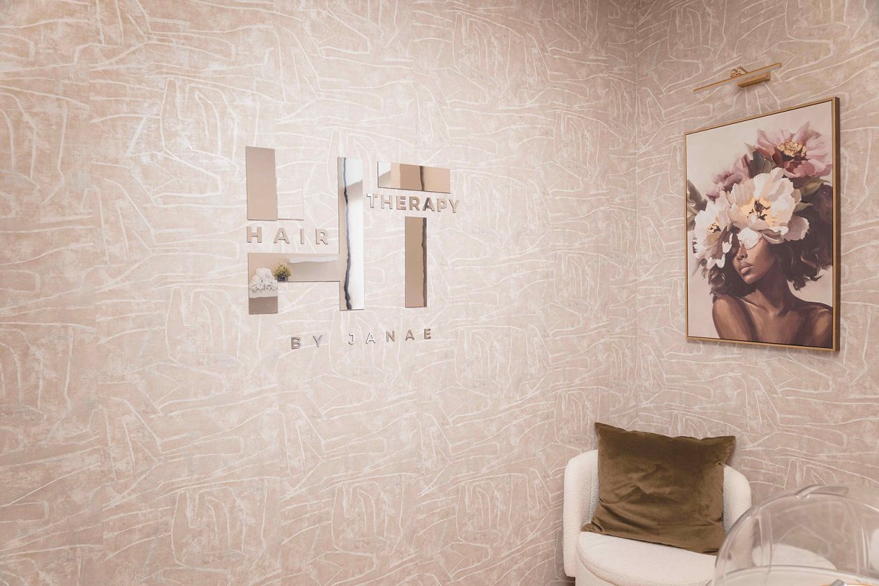 Private salon suite at WanderLux with a custom mirrored logo wall and blush textured wallpaper