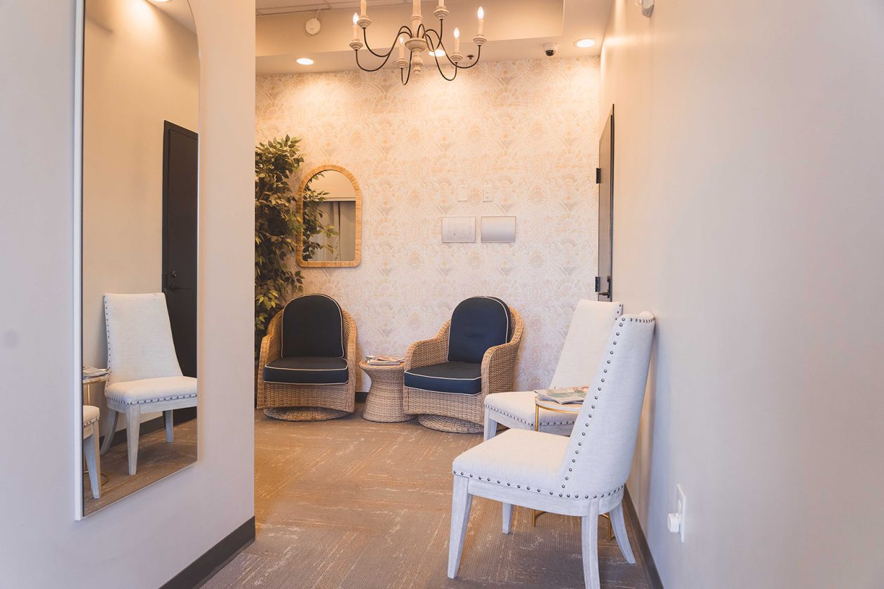 Reception and waiting lounge at WanderLux University Hill with upholstered chairs and a chandelier