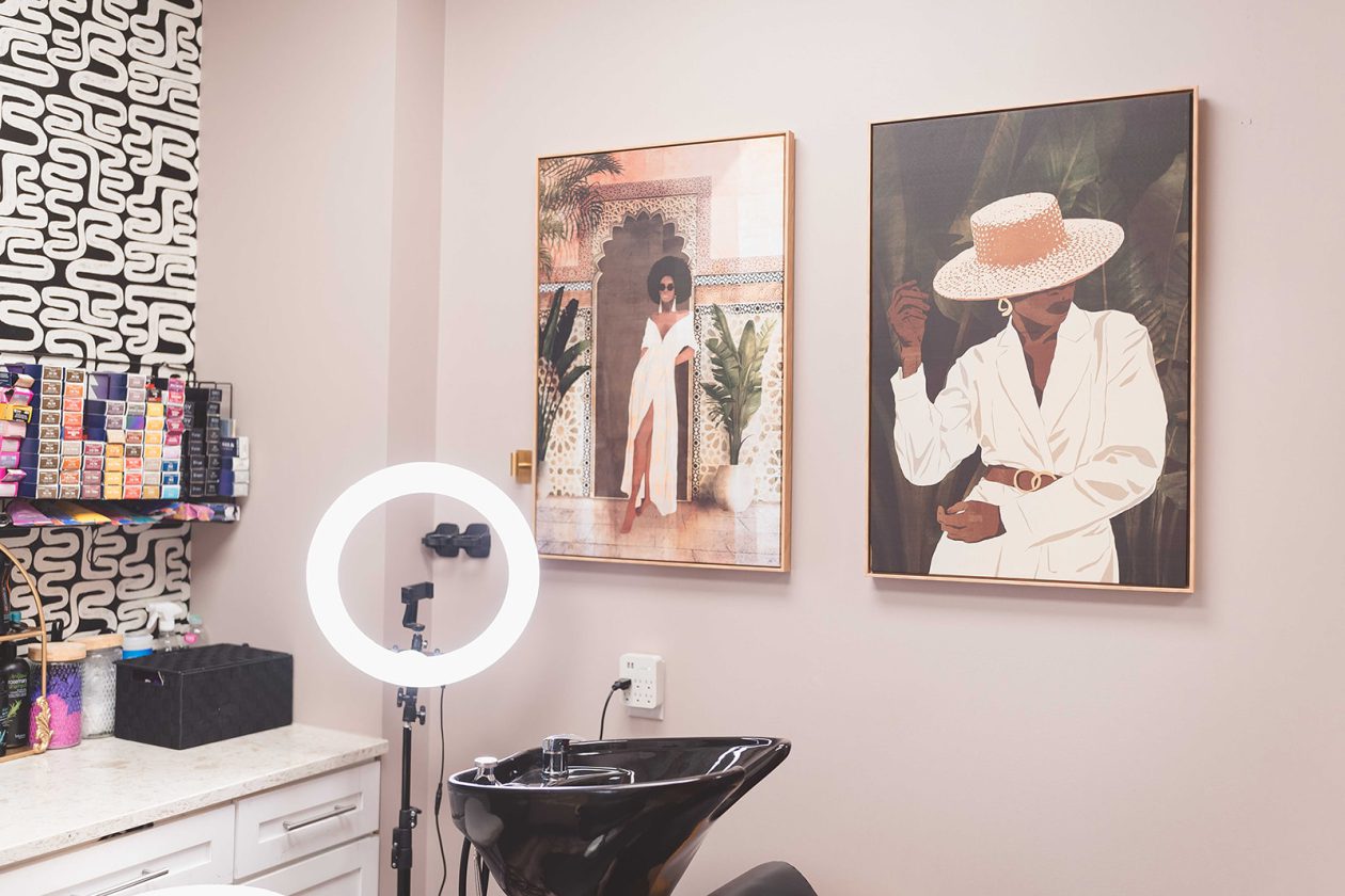 WanderLux suite at University Hill with patterned pink walls, a ring light and shampoo bowl